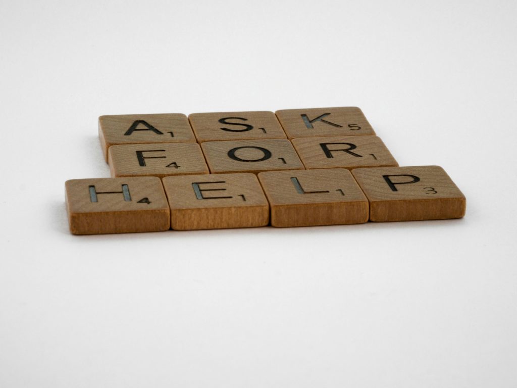 Scrabble tiles arranged on a white background forming the phrase 'Ask for Help', conveying a message of communication.
