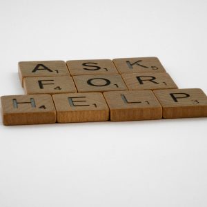 Scrabble tiles arranged on a white background forming the phrase 'Ask for Help', conveying a message of communication.
